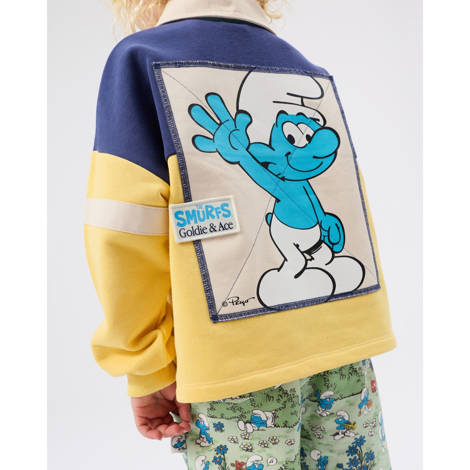 Boy wearing Goldie & Ace x The Smurfs rugby shirt, playing outdoors