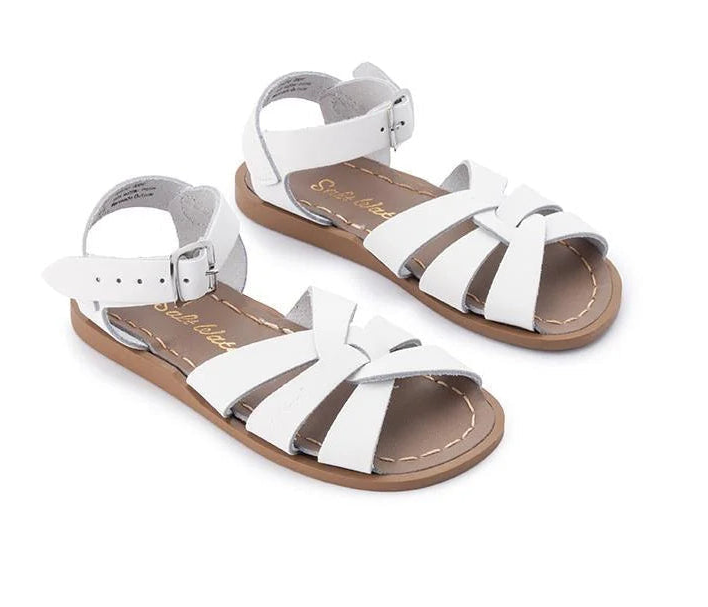 A pair of white leather children's slide sandals with brown soles, shown on a plain white background.